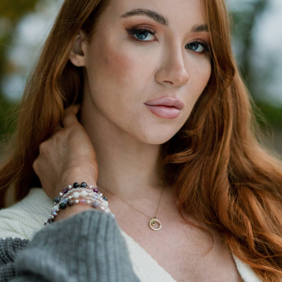 Model wearing gold necklace with diamond and sapphire.