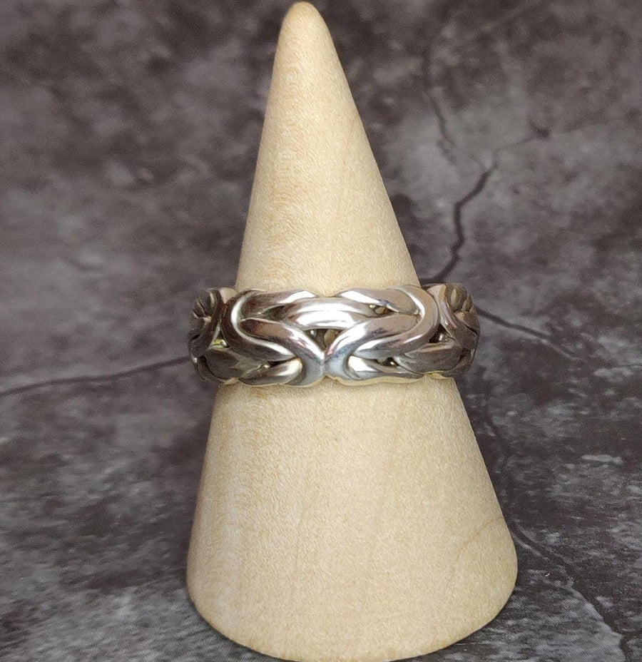 Side view of a king chain style silver ring on a wooden display cone.