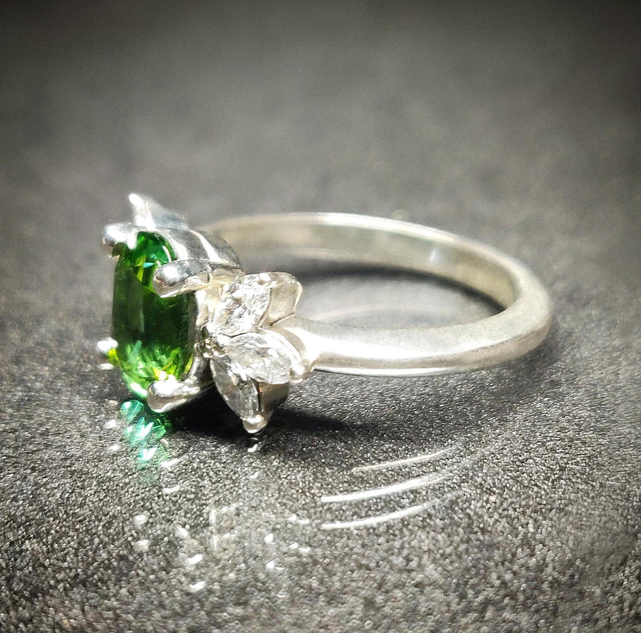 Side view of a white gold engagement ring with lab grown diamonds and green tourmaline.