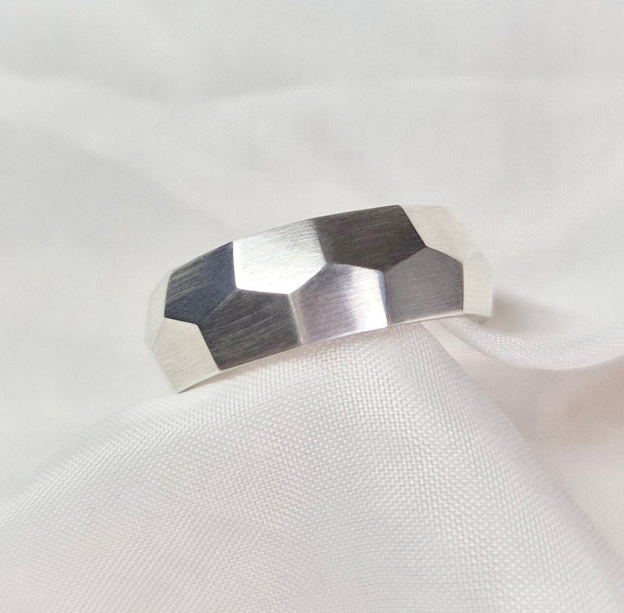 Faceted hexagonal texture ring on a white cloth background.
