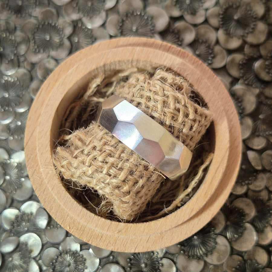 Hammered texture argentium silver ring on some jute in a display box.