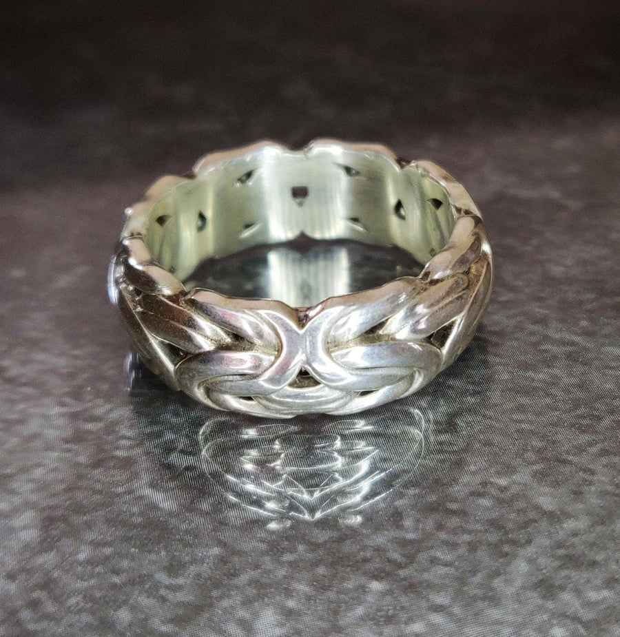 Byzantine king chain style ring in argentium silver on a reflective table.