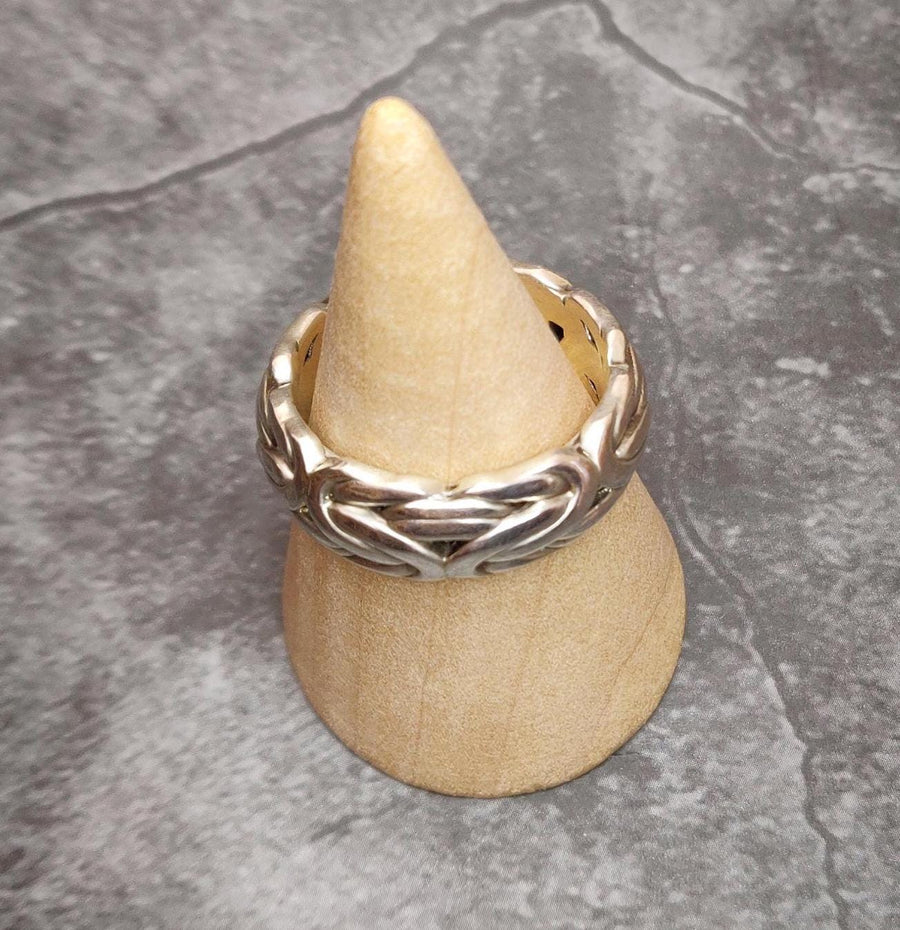 Top view of a byzantine chain link style silver ring on a wooden display cone.