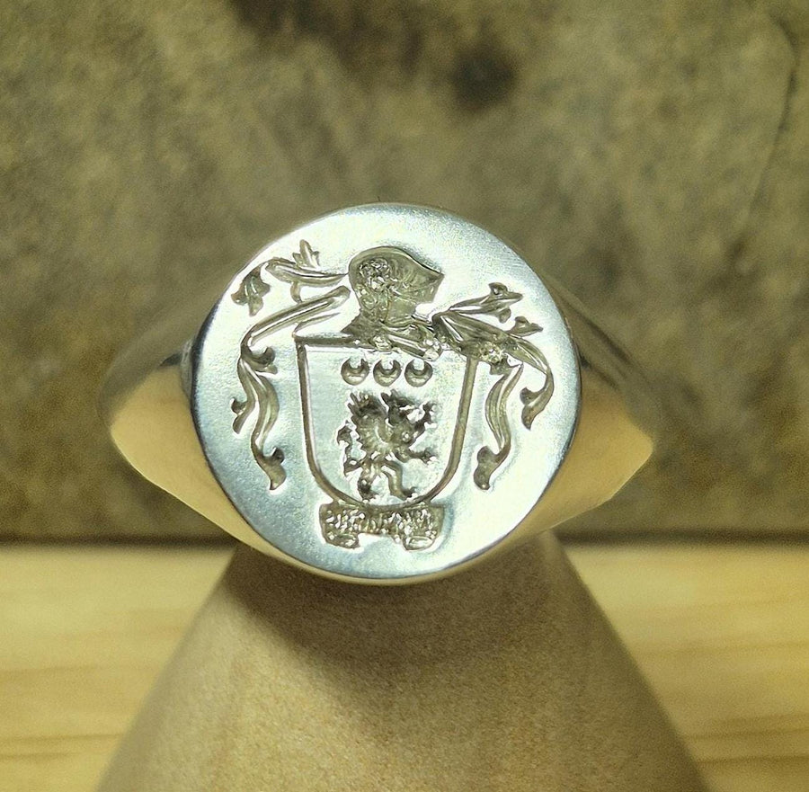 Coat of arms argentium silver signet ring on a wooden stand.