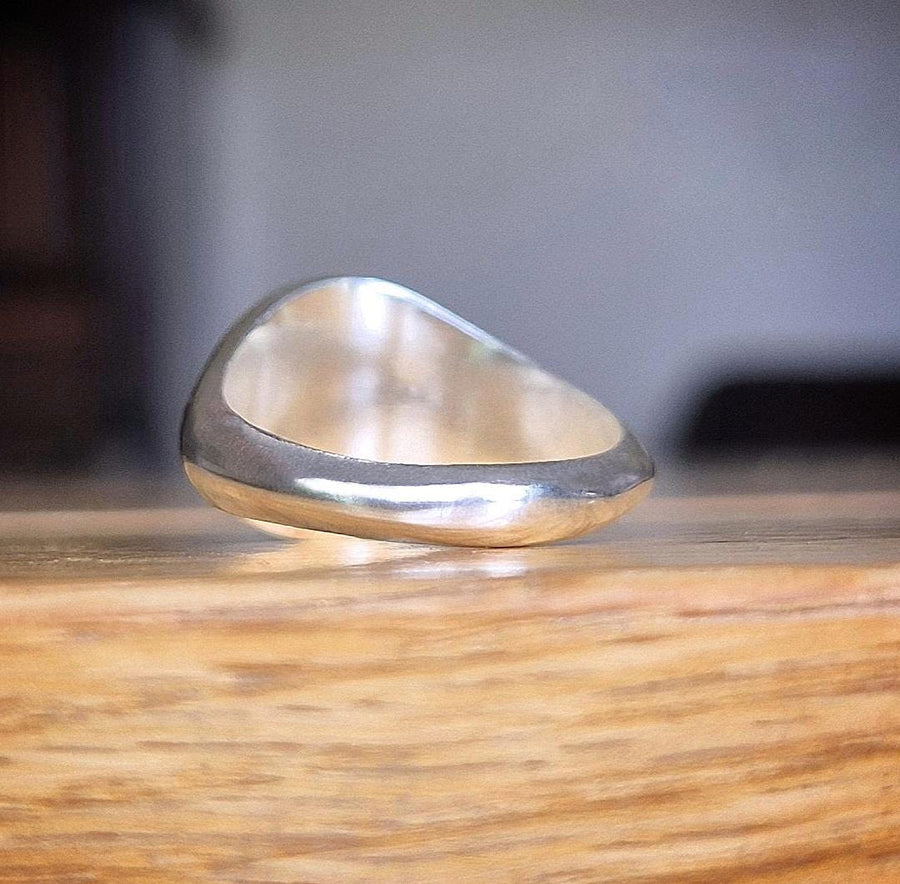 rear view of a silver signet ring on a wooden table