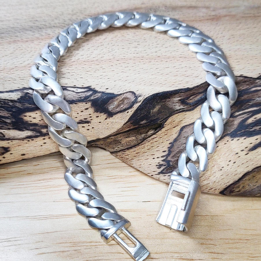 chunky curb bracelet open on a wooden block