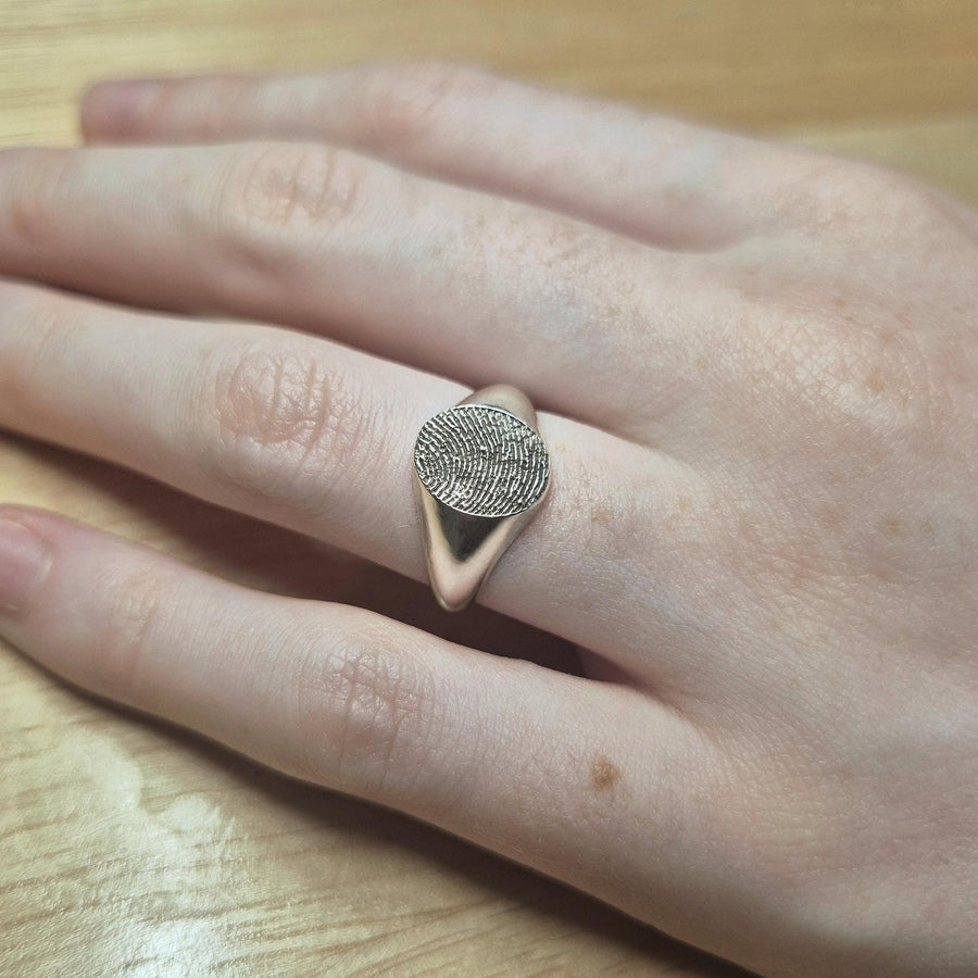 Hand wearing an argentium sterling silver signet ring with an etched fingerprint