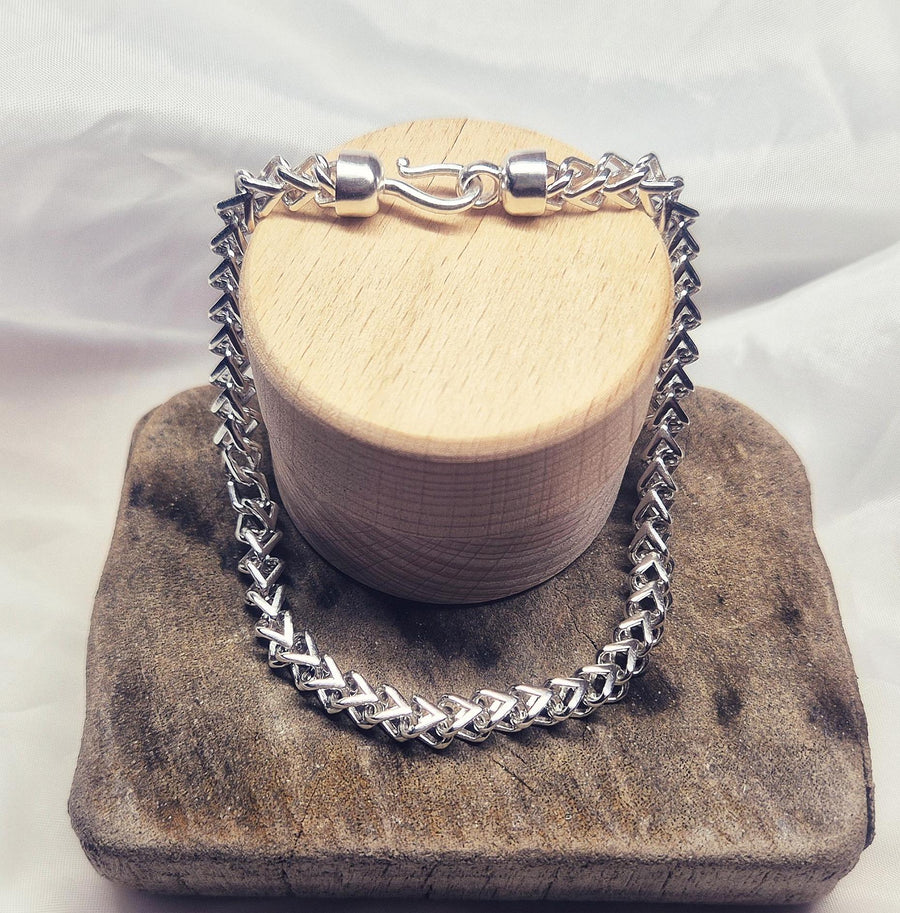 argentium silver double cross bracelet on a wooden display