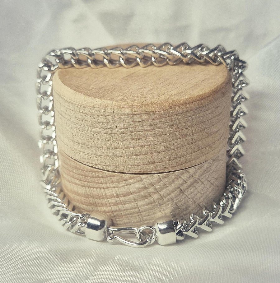 argentium sterling silver double cross bracelet on a wooden display.