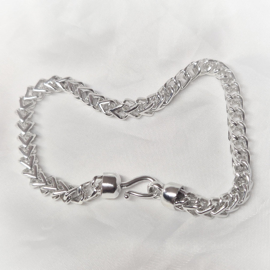 Top view of a double cross pirate hook argentium silver bracelet on a white background