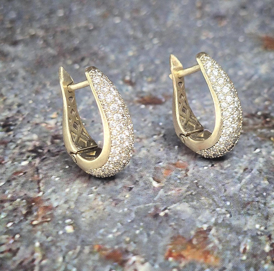 side view of 18k gold and diamond earrings on a stone background