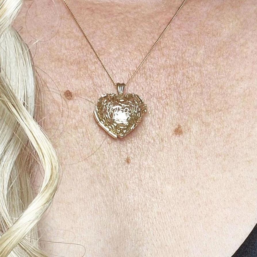 Model wearing the Sleepy Fox in a Hedgerow gold heart locket necklace with fine chain, shown against skin and curled blonde hair.