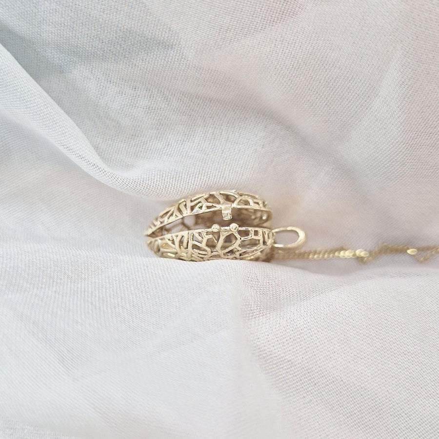 Closed Sleepy Fox in a Hedgerow locket pendant viewed from the side, showing its intricate gold hedgerow pattern.