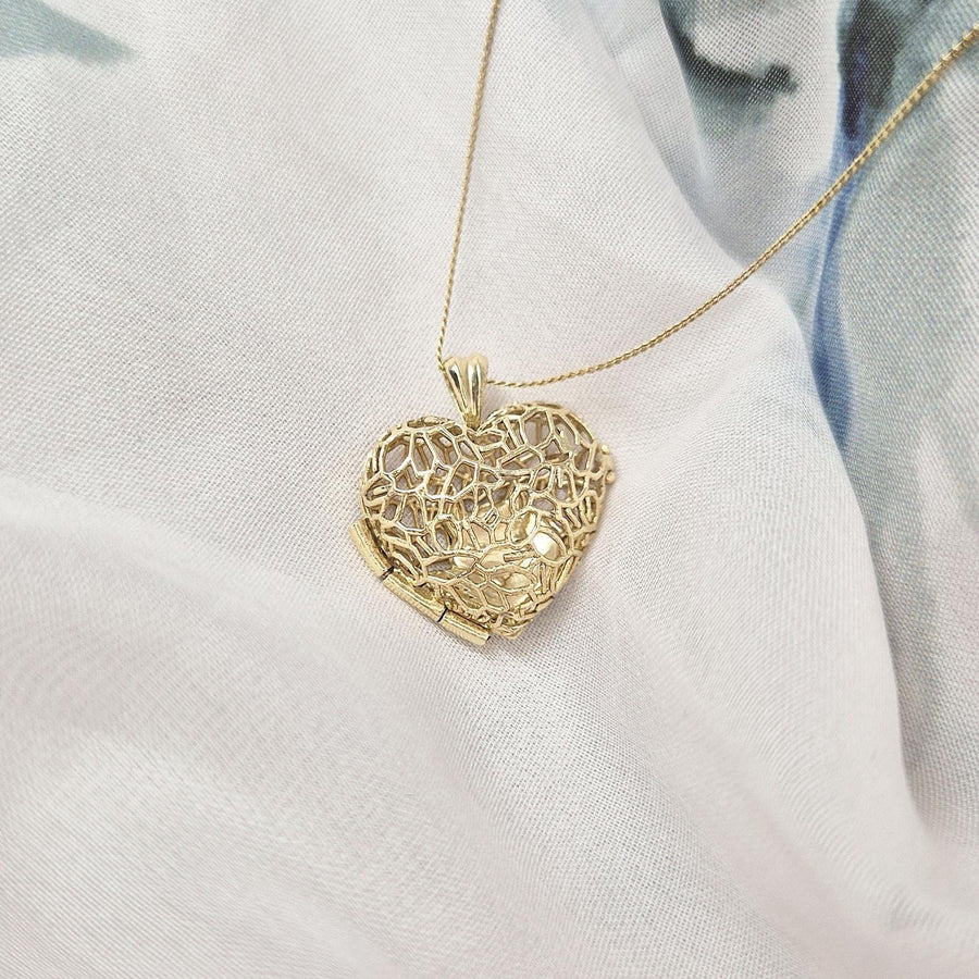 Closed Sleepy Fox in a Hedgerow heart locket with gold filigree detailing, resting on white and blue fabric.