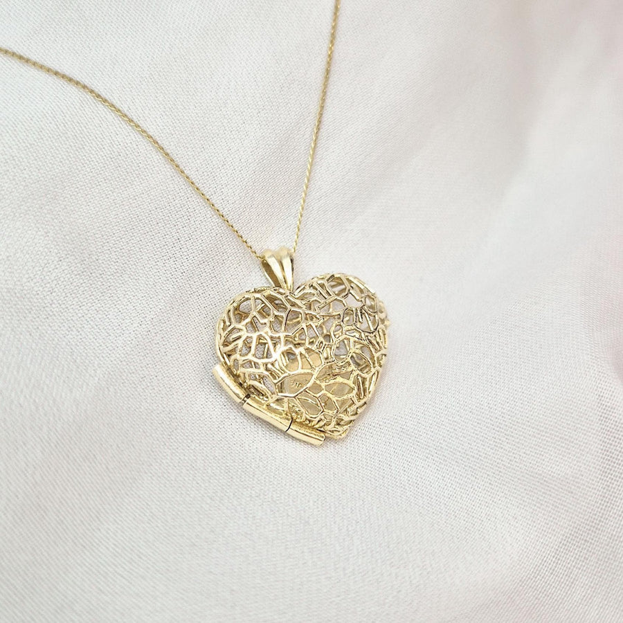 Elegant Sleepy Fox in a Hedgerow gold locket necklace with intricate openwork heart design on white and pink fabric.