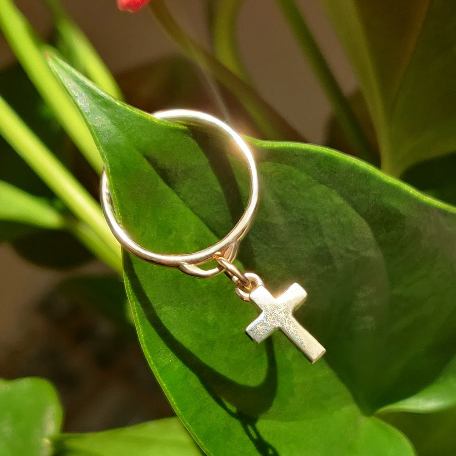 gold cross drop ring on a leaf