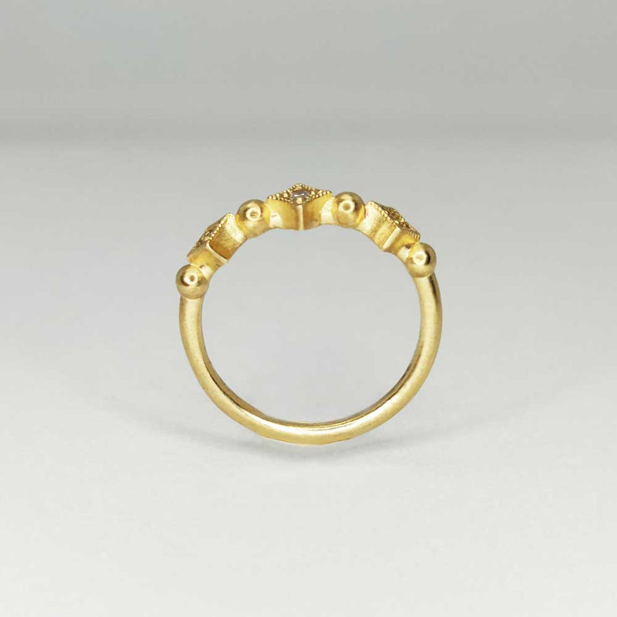 Profile view of gold milgrain sapphire ring on white background