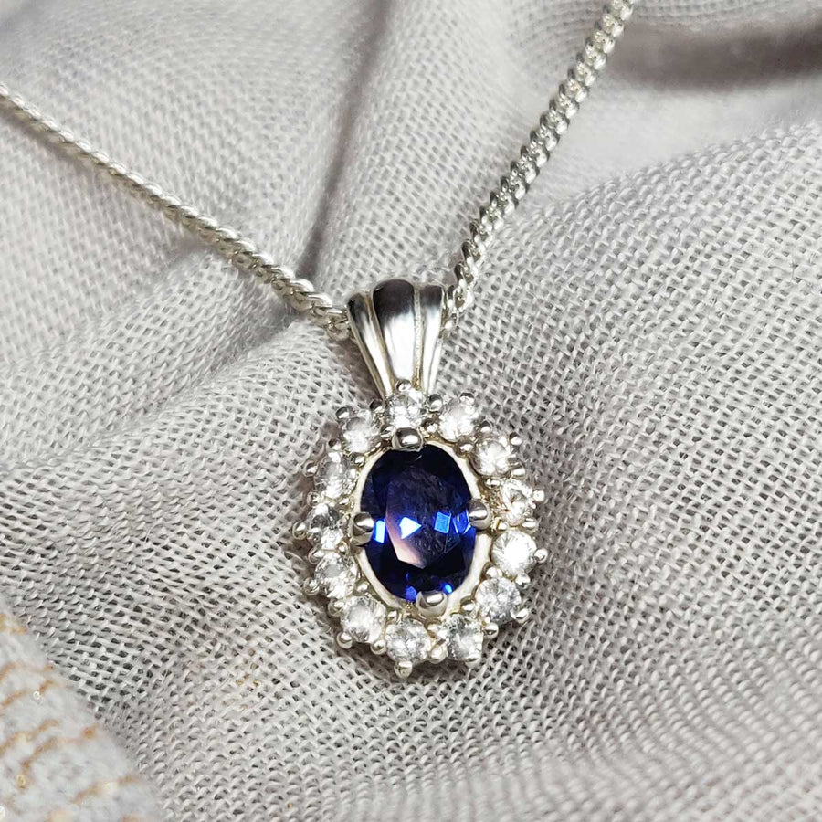 Blue and white sapphire cluster necklace in argentium silver on cloth background