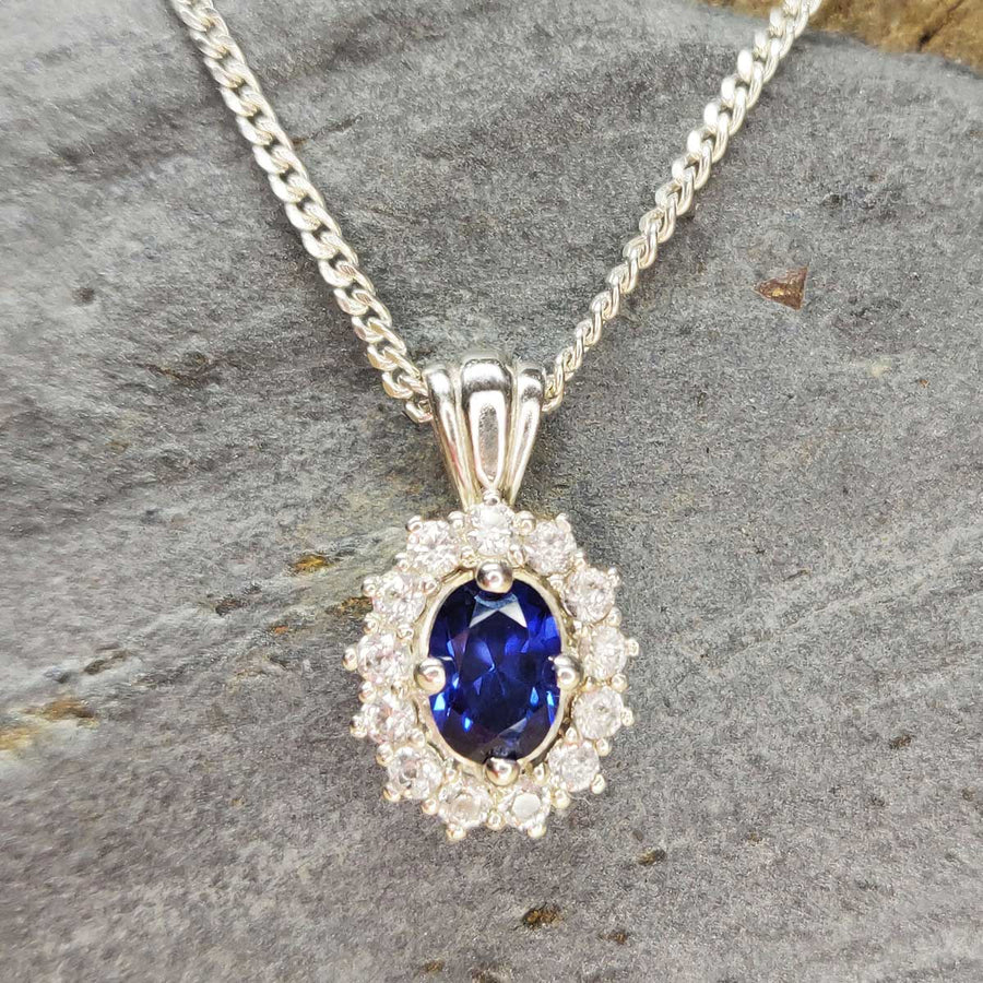Blue and white sapphire cluster necklace in argentium silver on slate background