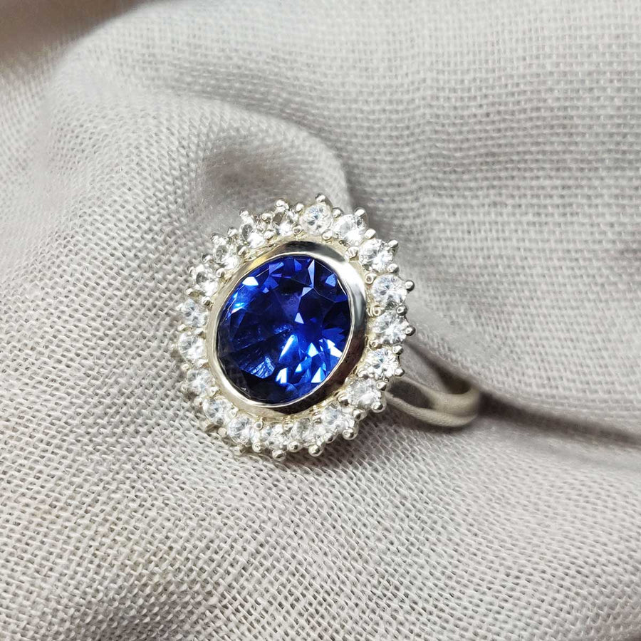 Blue and white sapphire cluster ring in argentium silver on cloth background