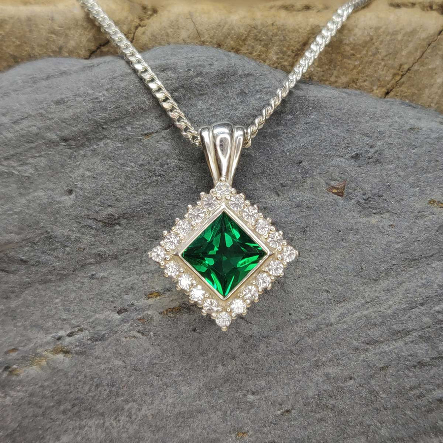 Princess cut emerald and white sapphire cluster necklace in argentium silver on slate background