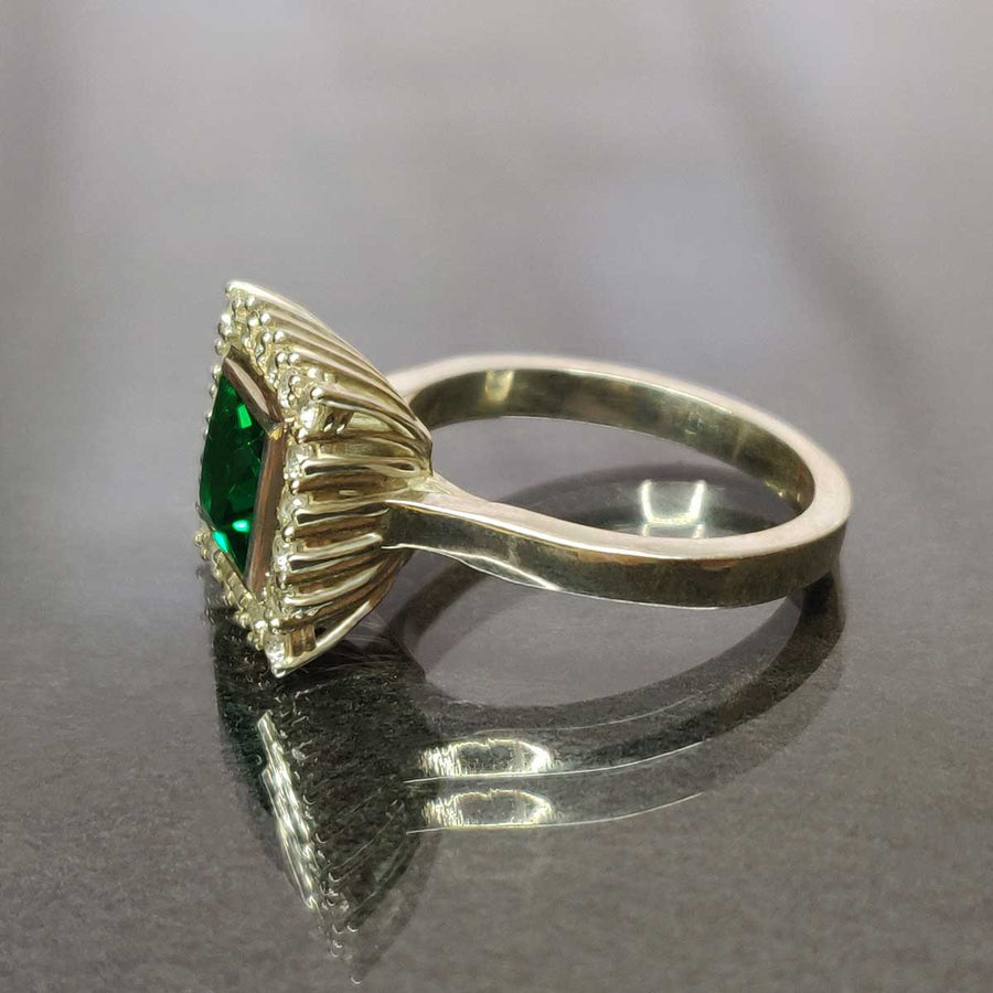 Princess cut emerald with white sapphire cluster in argentium silver from side on glass