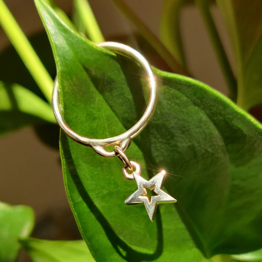 Gold drop ring with a star charm on green background