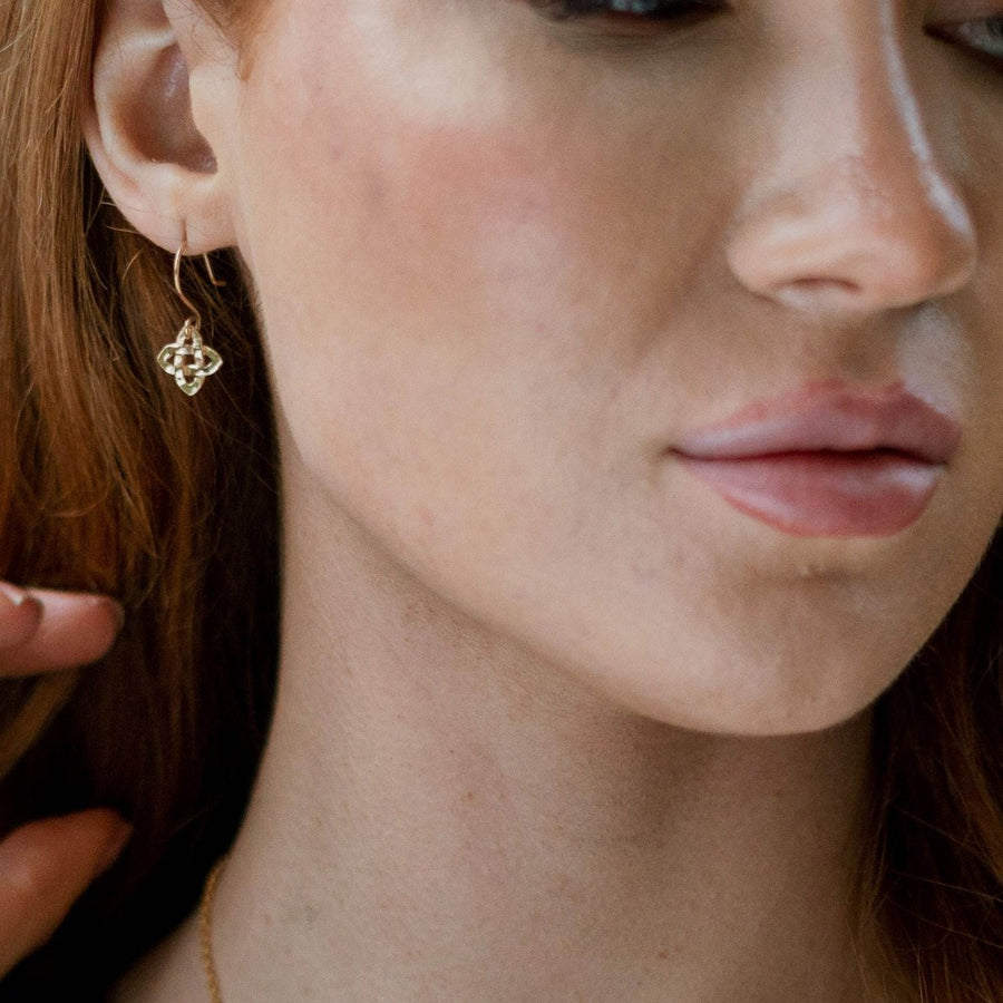 girl wearing gold celtic cross earring