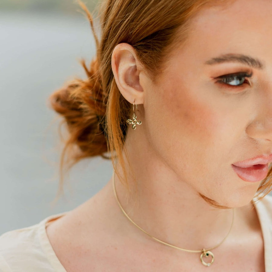 Girl wearing diagonal gold celtic earring and solasta omega necklace