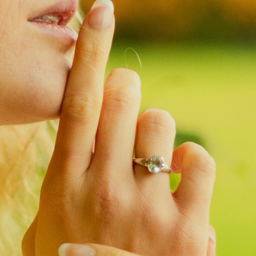 girl with finger to her lips wearing a silver aquamarine gemstone ring