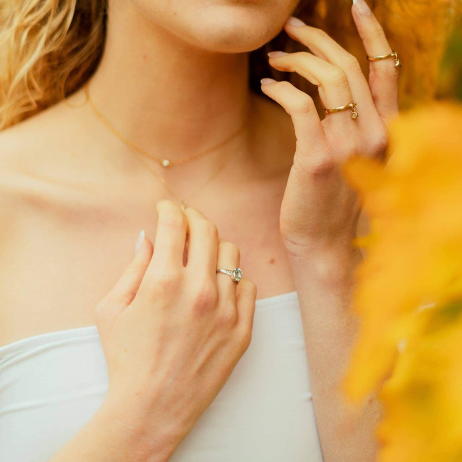 Girl wearing aquamarine gemstone ring, diamond drop ring and heart charm ring