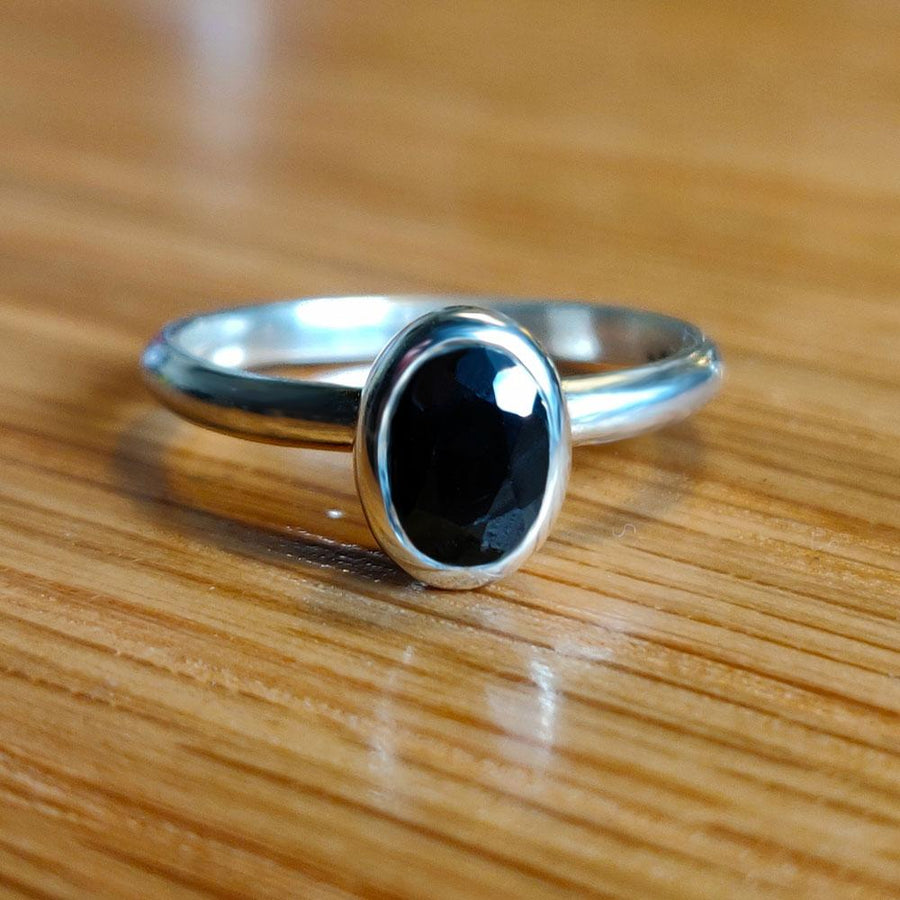 Black Sapphire Oval Ring in Argentium Silver on a Wooden Background
