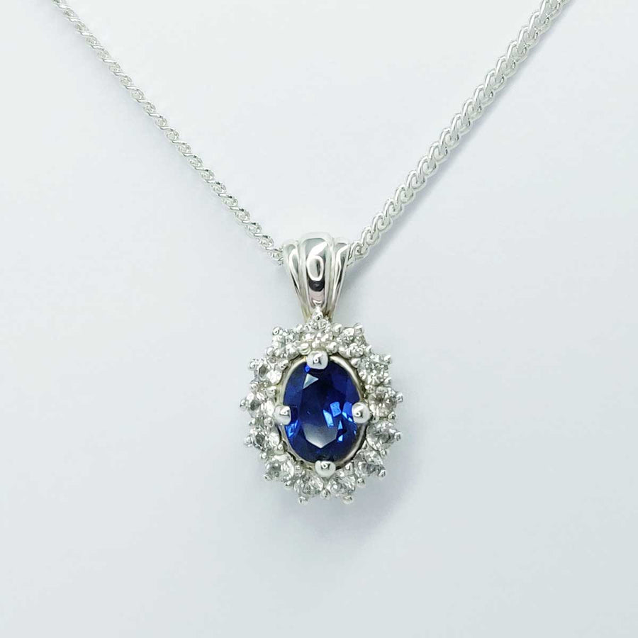 Blue and white sapphire cluster necklace in argentium silver on white background
