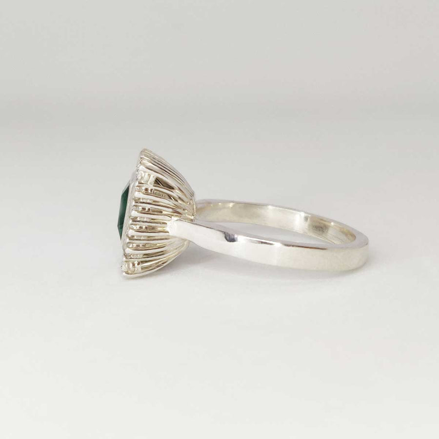 Princess cut emerald with white sapphire cluster in argentium silver on white background from side