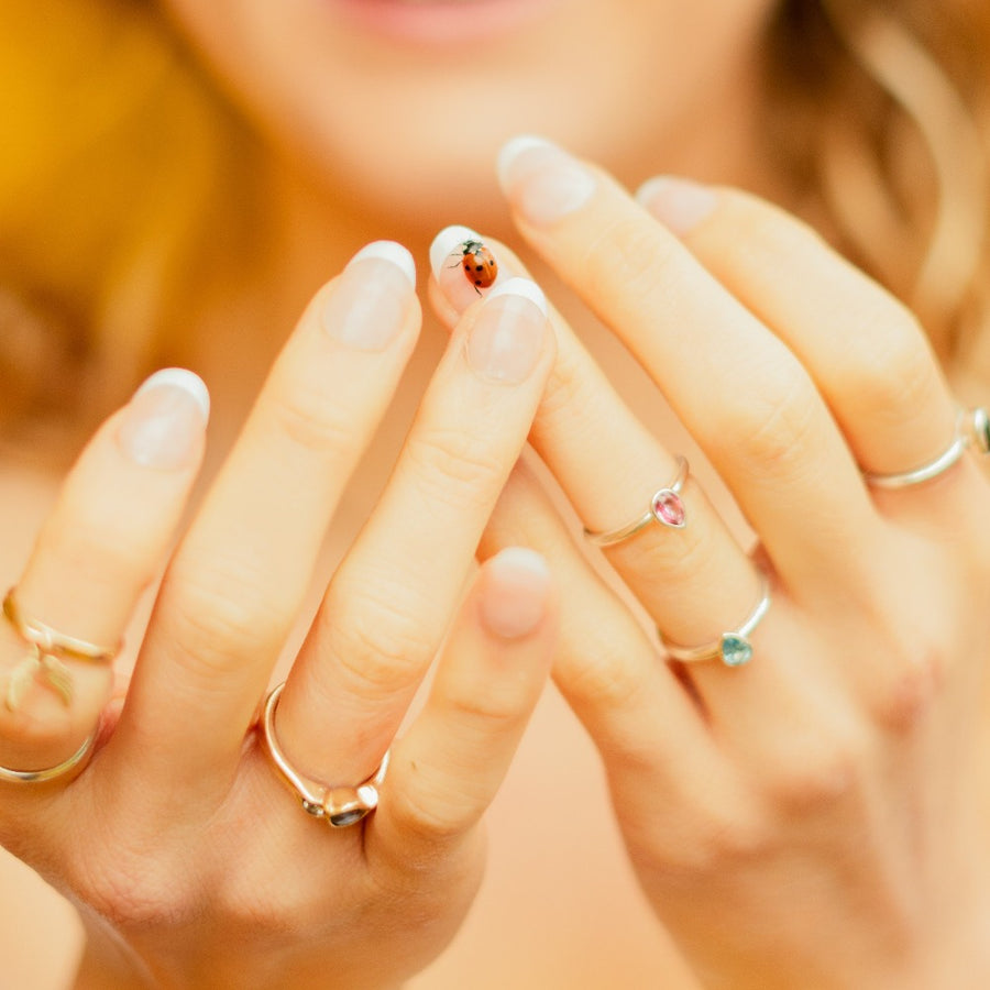 girl wearing multiple rings with a ladybird on her fingertip