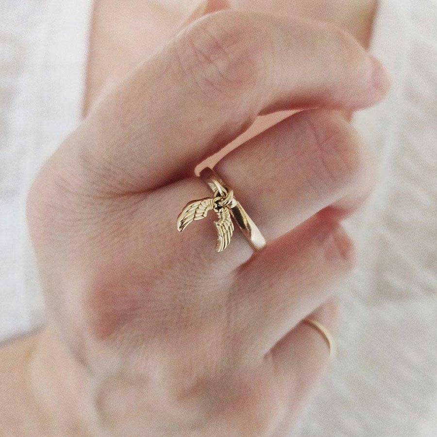 Gold angel wing charm ring on a hand